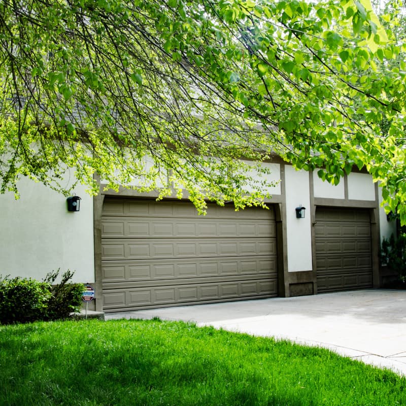 garage doors on a stucco house with wood trim
