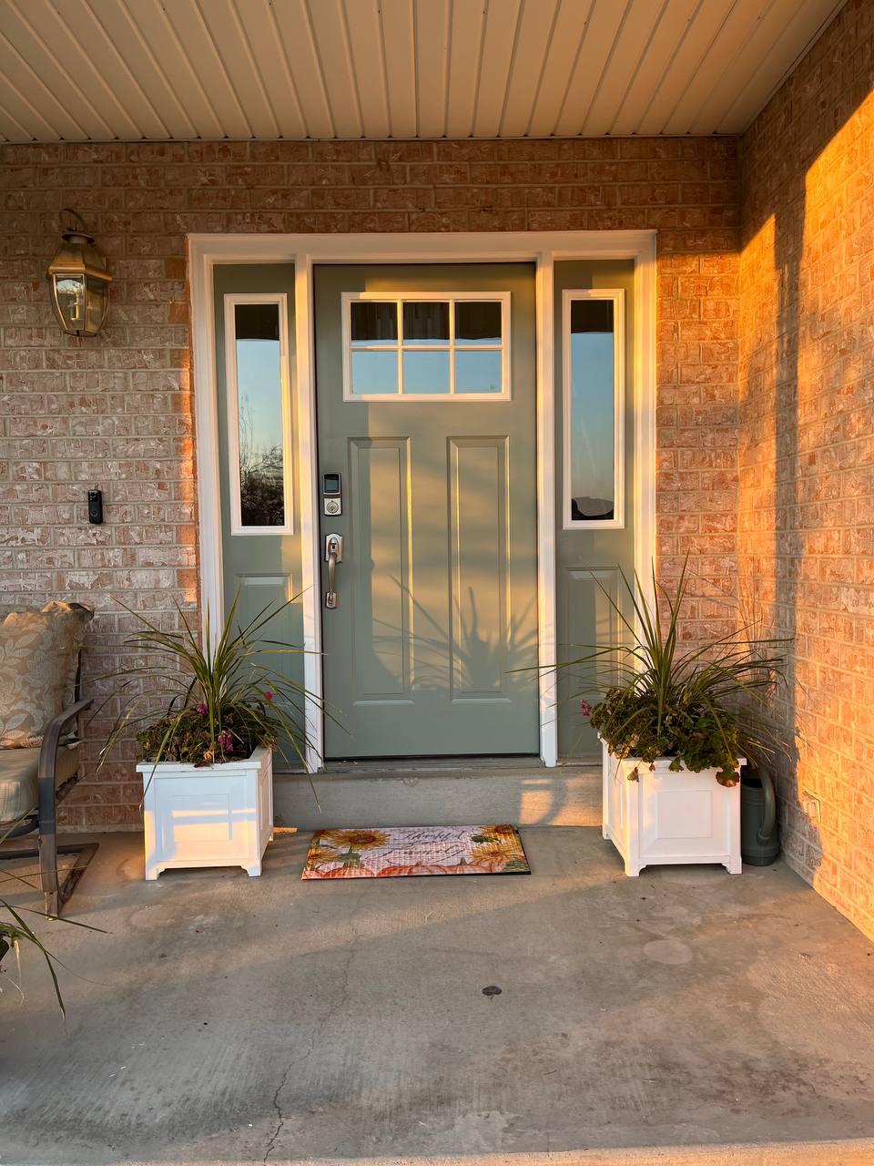 Exterior side of a front door to a house that has just been painted a sage green with white trim.