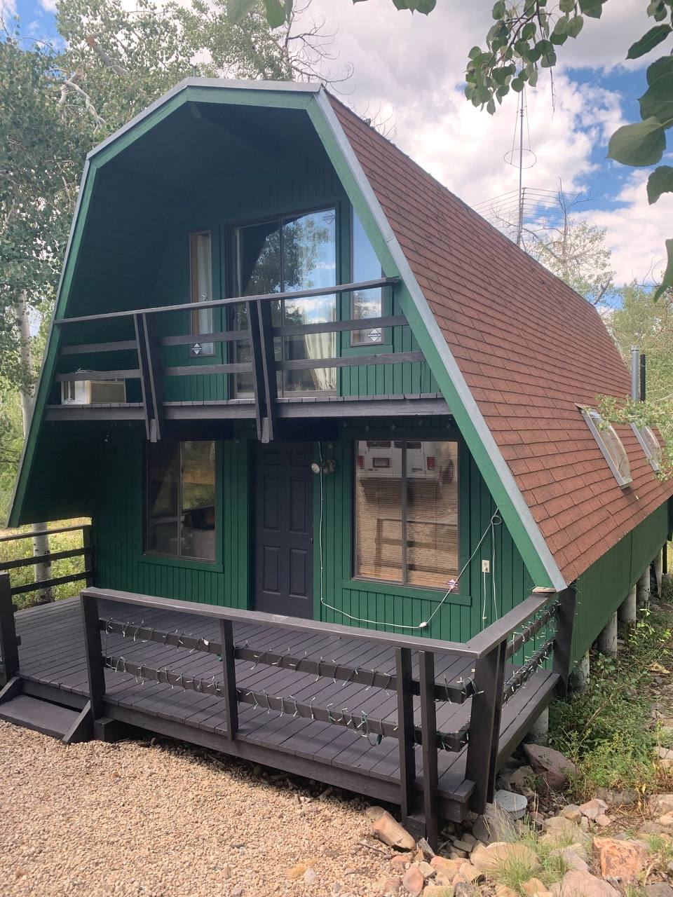 Cabin exterior that was recently painted green with a brown accenting deck.