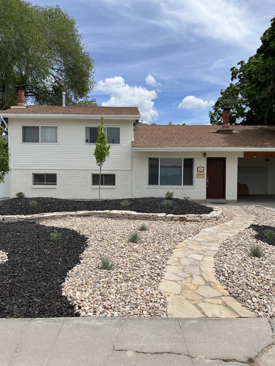 The exterior of a multi-level house that has white brick and siding.