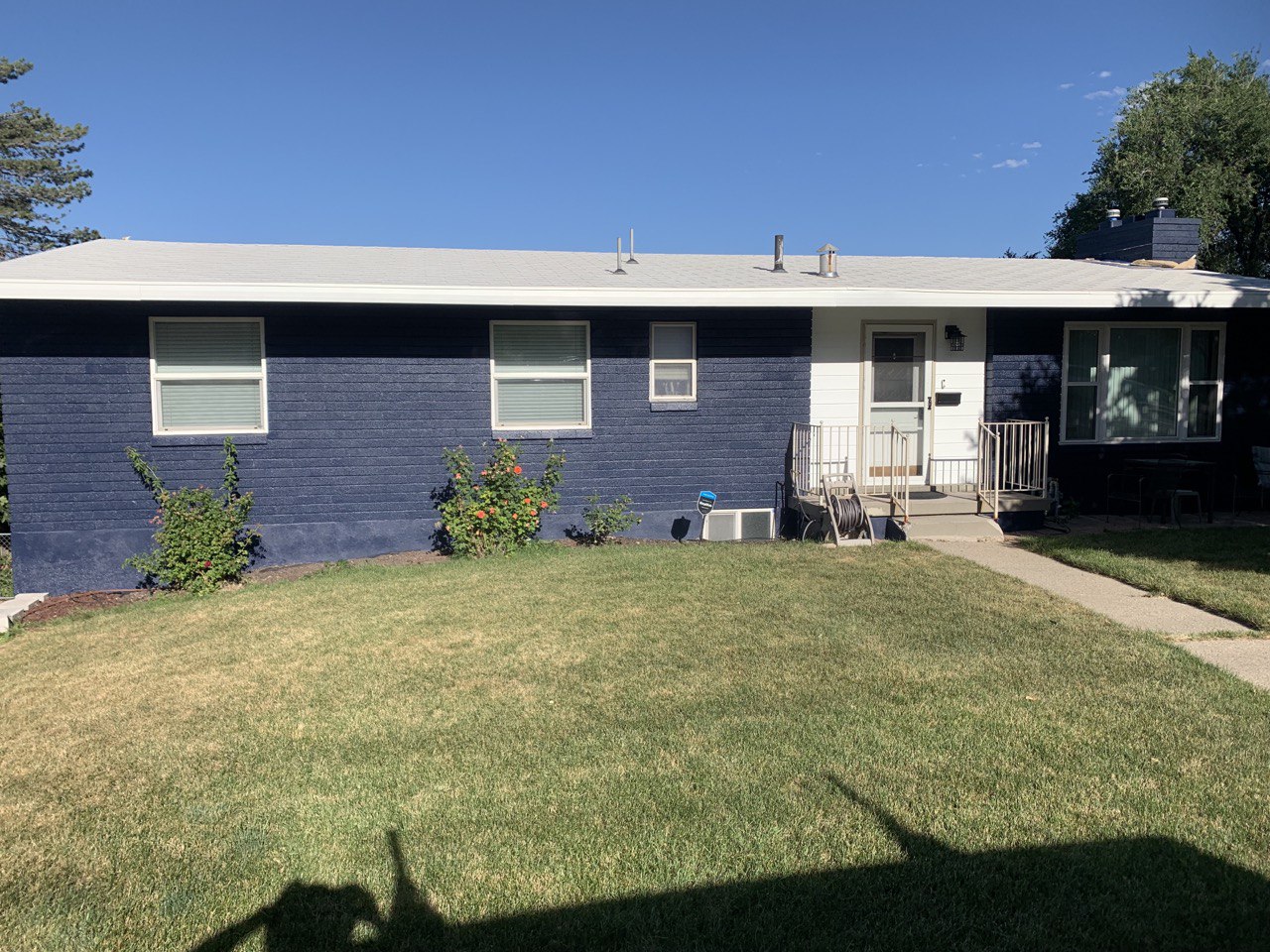 Exterior of a brick house that has been painted navy blue with white accents.